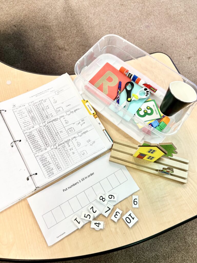 Data sheet in binder, clear tub with letter cards, scissors, glue, number 3 card, house, tree and boy to work on prepositions