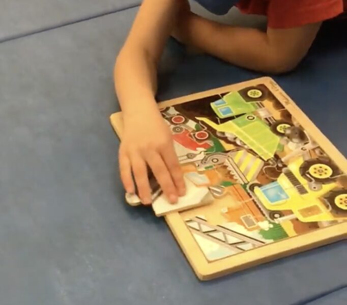 student completing a puzzle laying over a yoga ball on their stomach