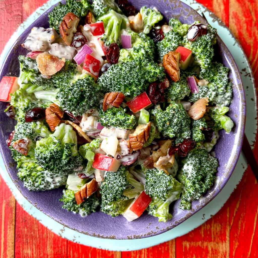 Summer Broccoli Crunch Salad in purple bowl on red wooden table