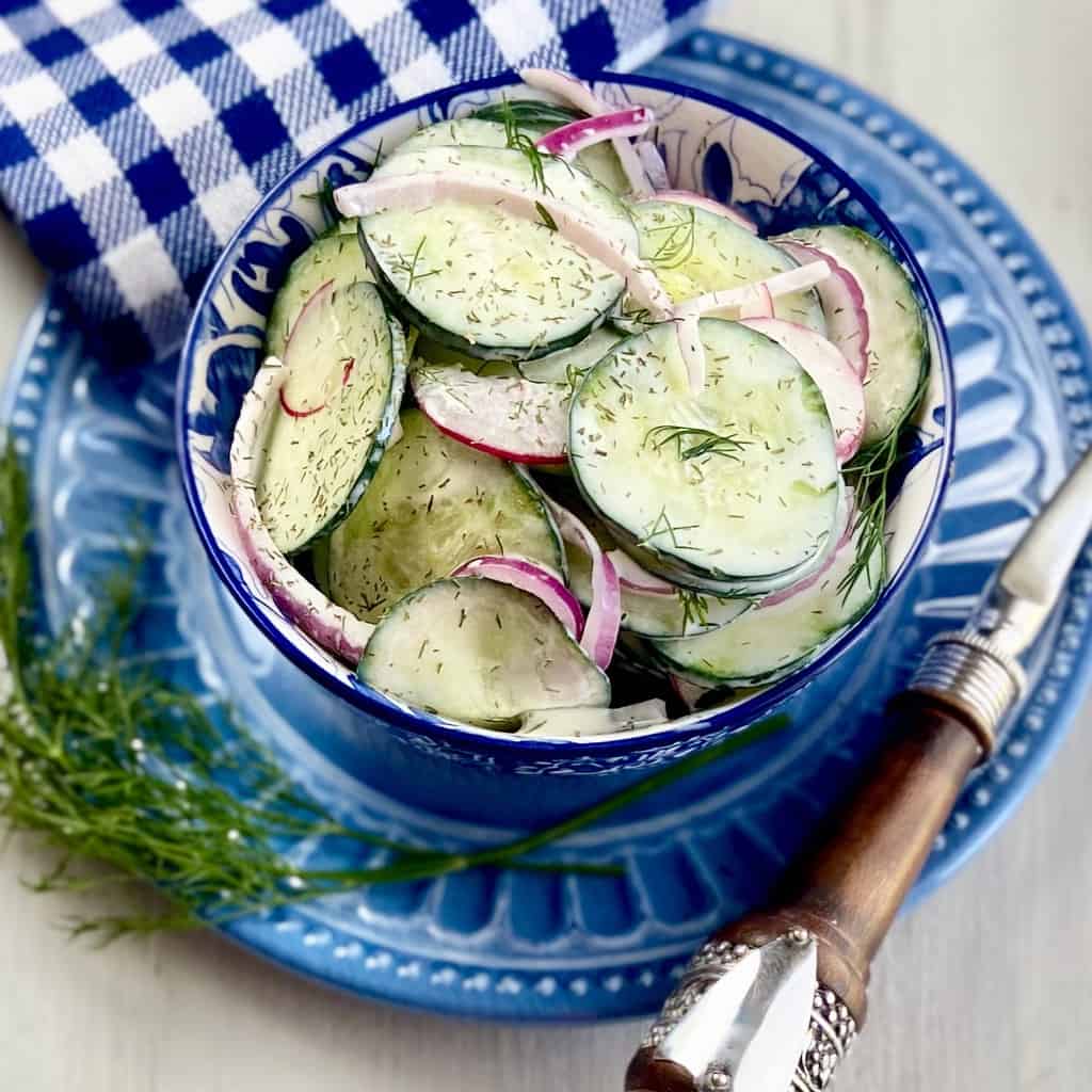 Cucumber salad in decorative blue bowl.