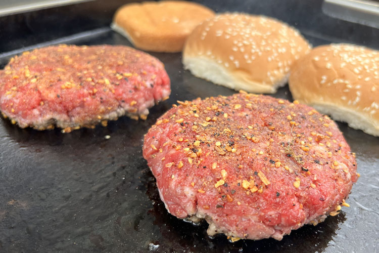 patties cooking on the grill with burger buns