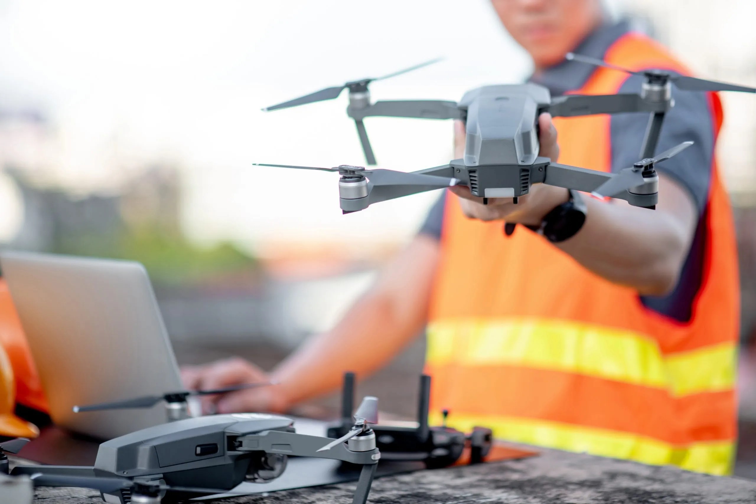 Young engineer man working with drone laptop and smartphone at work site. Using unmanned aerial