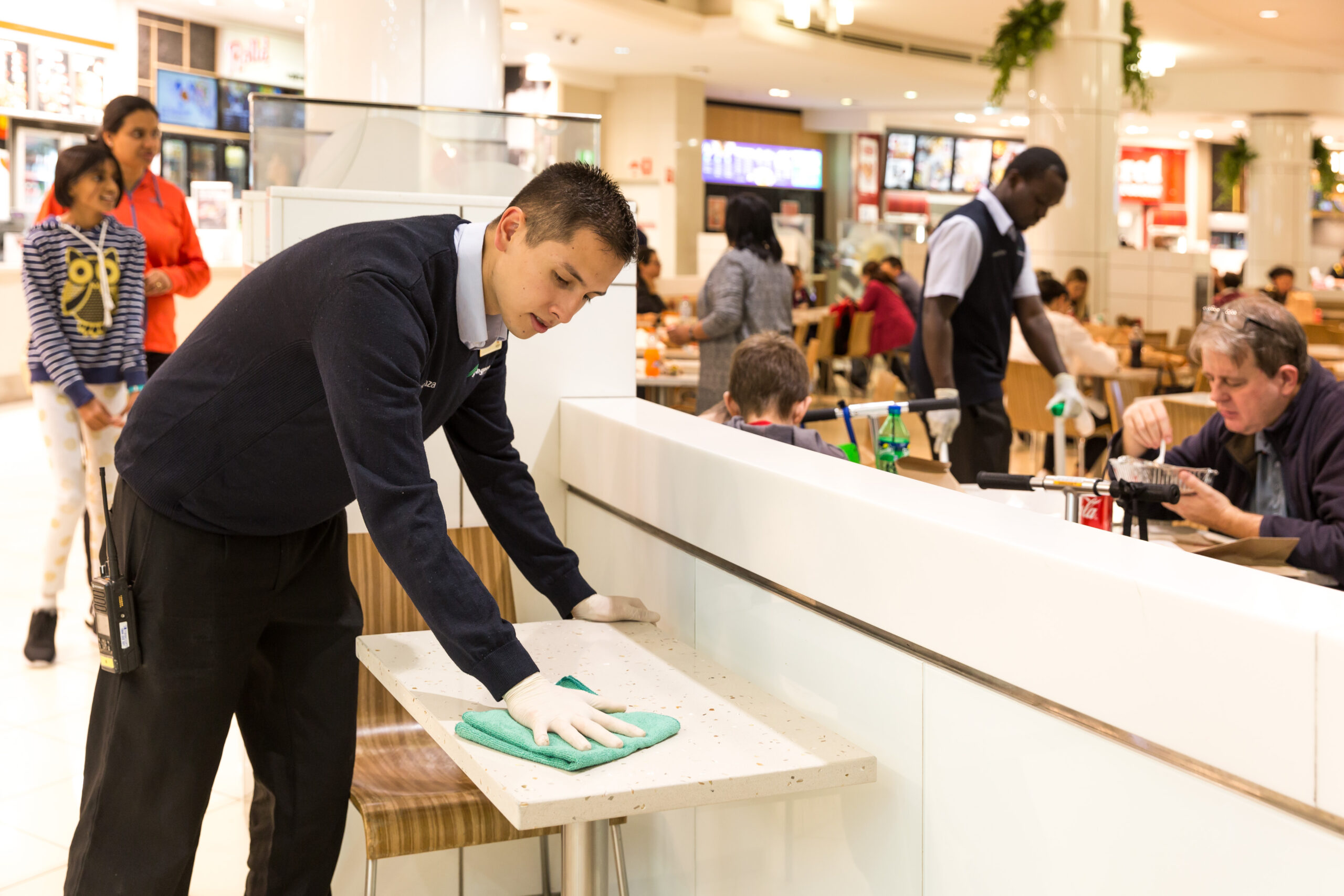 Close up Male Springmount Team member cleaning table in food court