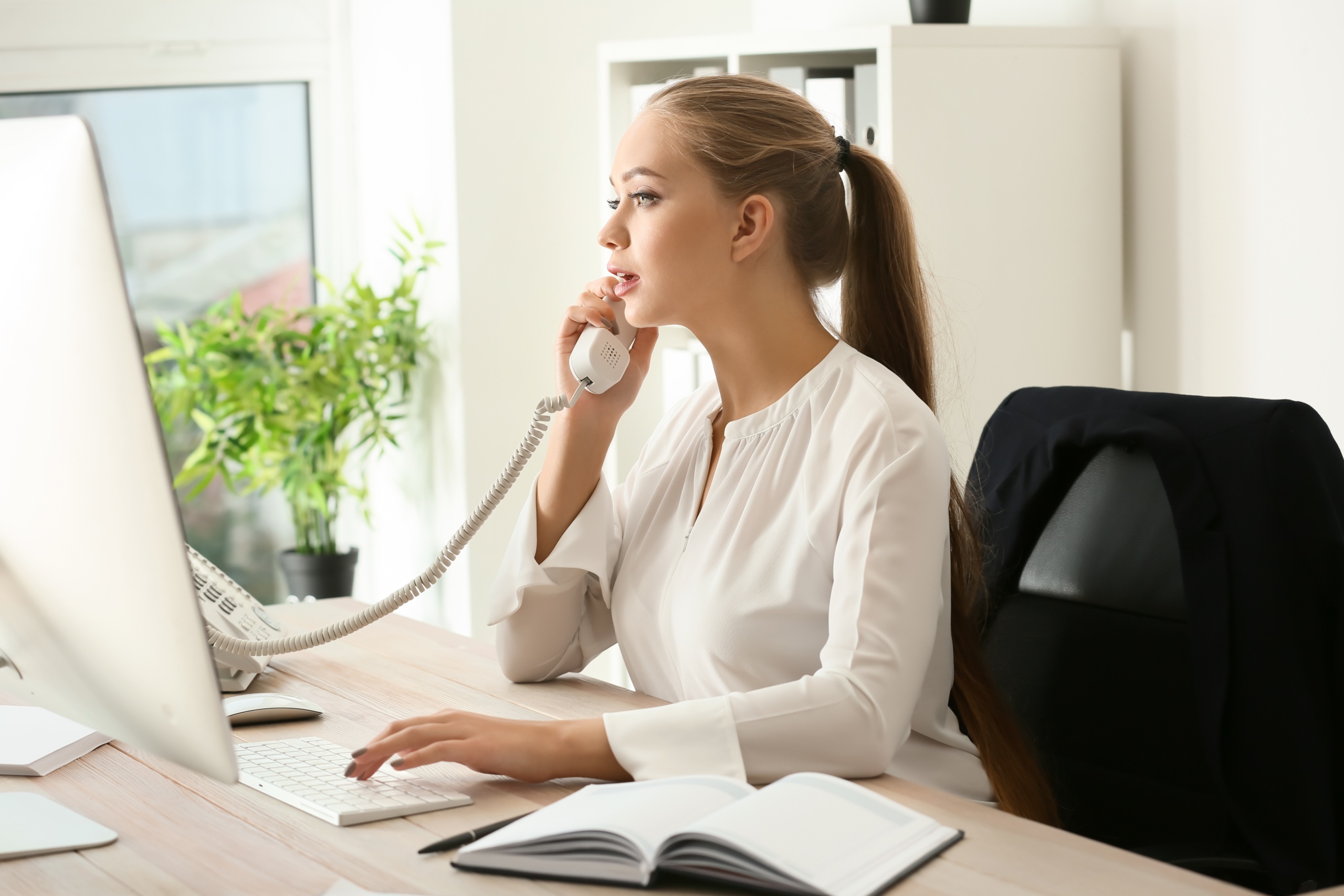 Beautiful female secretary talking on telephone in office StartHouse