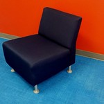 black chair, red wall and blue carpet. inside of an office.