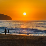 Soft hazy sunrise seascape, orange sky, people silhouettes and full sun