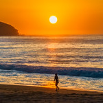 Soft hazy sunrise seascape, orange sky, woman silhouette and full sun