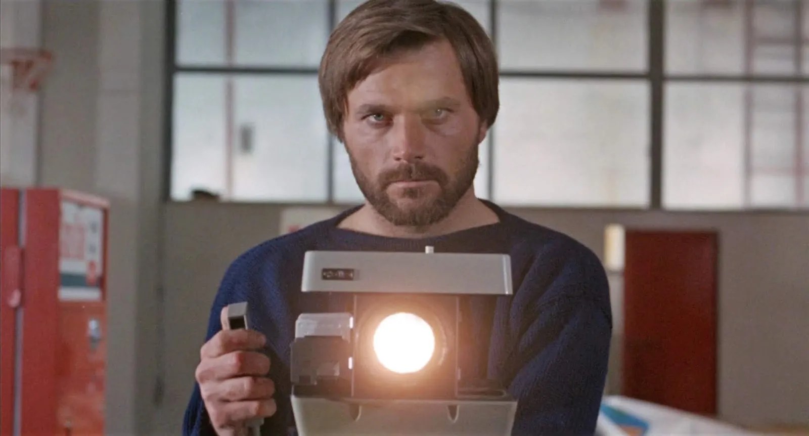 A Quiet Place In The Country Still man in white room with red accents sitting behind flash camera taking a picture