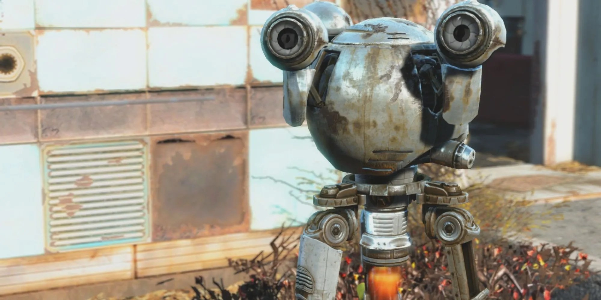 Fallout&rsquo;s Codsworth droid is dirty and rusty. In the background is a paneled wall that is rusted and some dead shrubbery