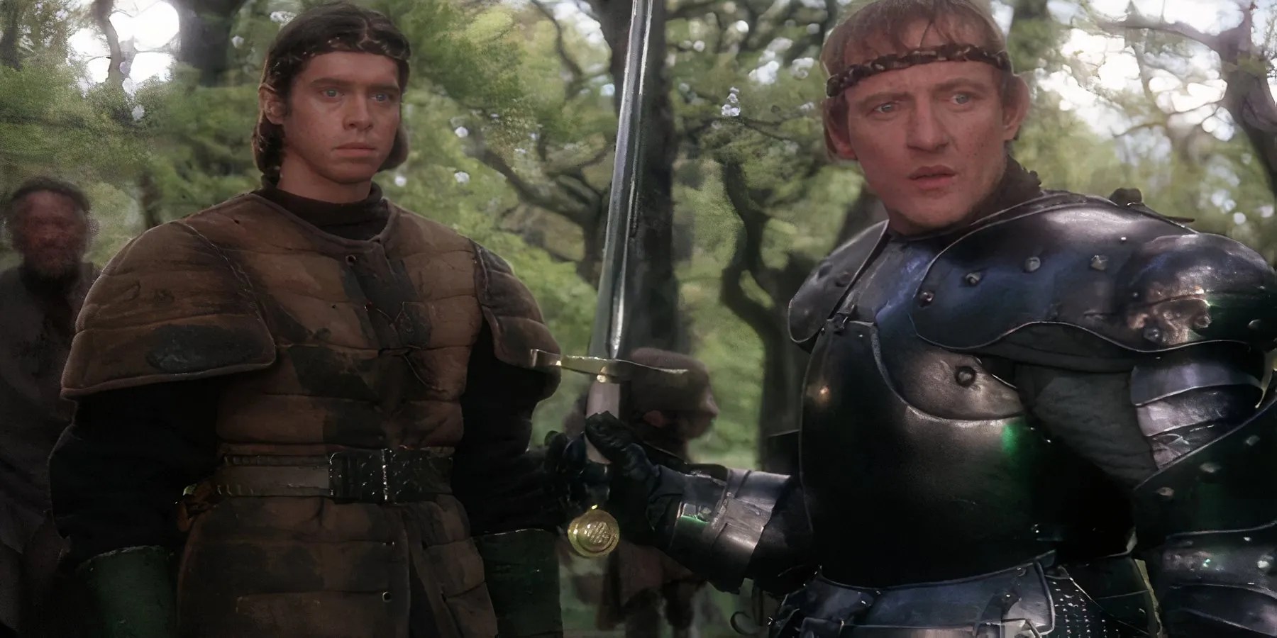 King Arthur pulls the sword out of the stone as he stands next to Sir Kay in Excalibur