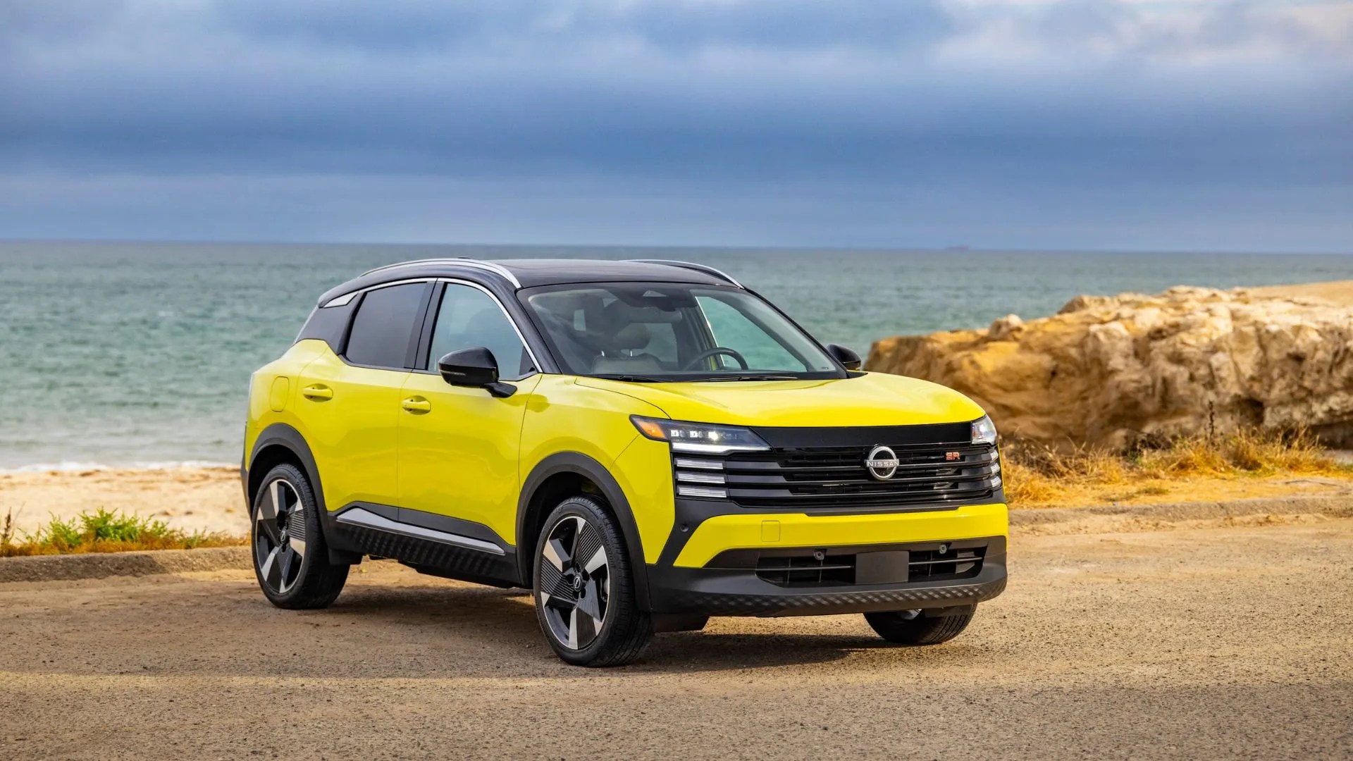 Front 3/4 shot of a yellow 2025 Nissan Kicks parked with the ocean in the background.