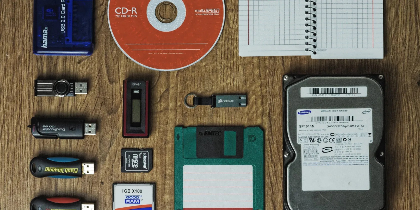 CD, hard drive, flash drive, and floppy disk on a wooden surface