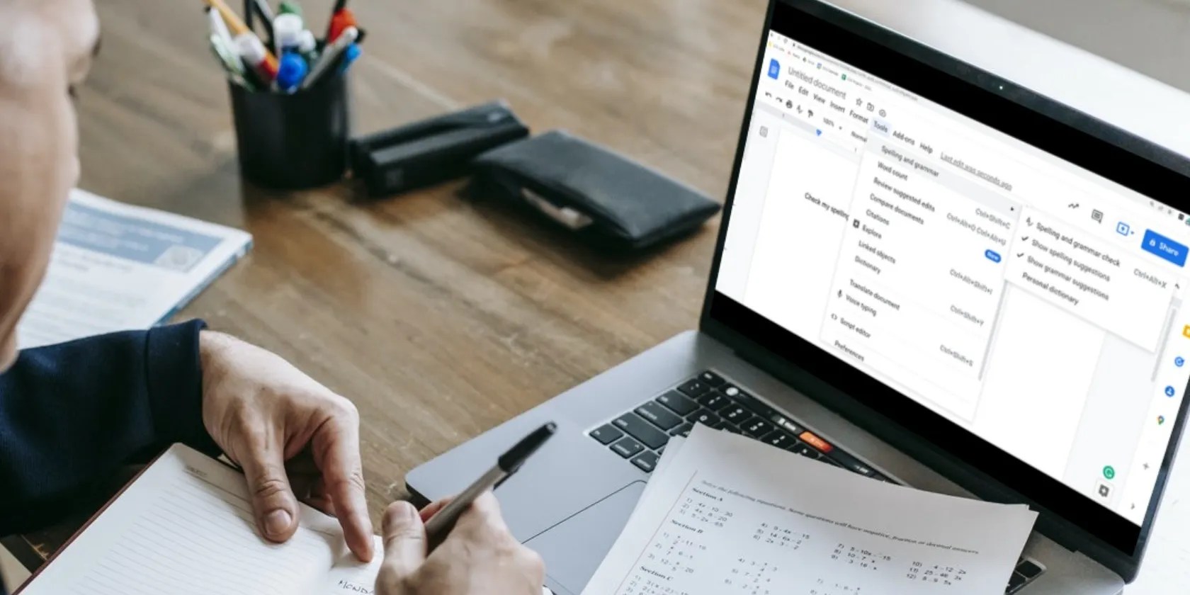 Image shows a man sitting at a desk using the Google spellcheck and writing in a journal