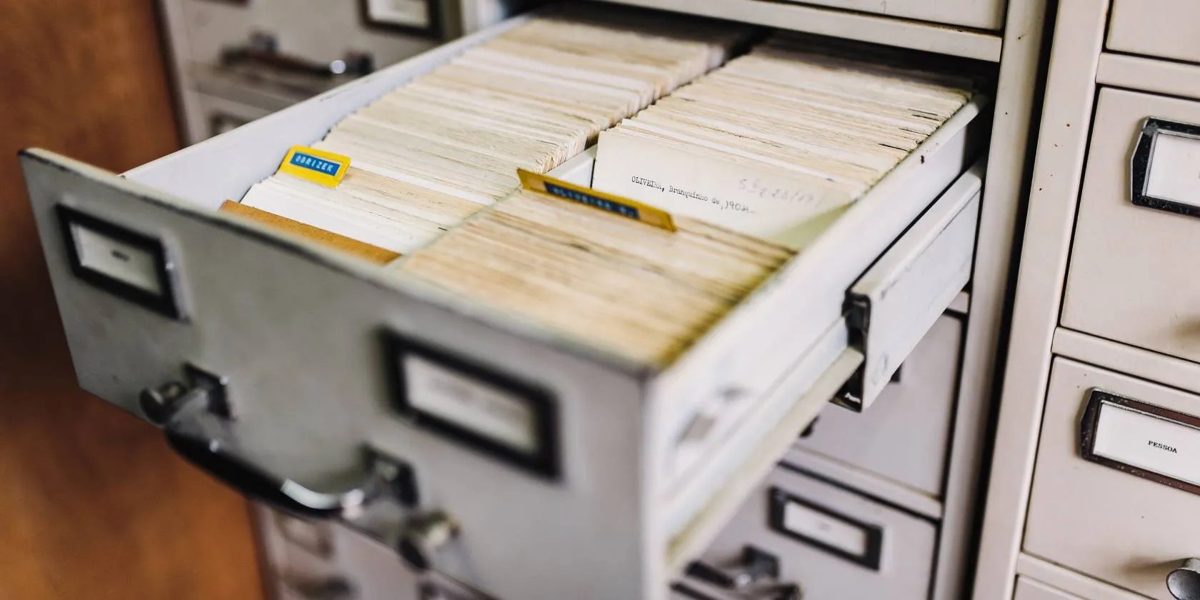 A close up of an open filing cabinet drawer containing many individual cards