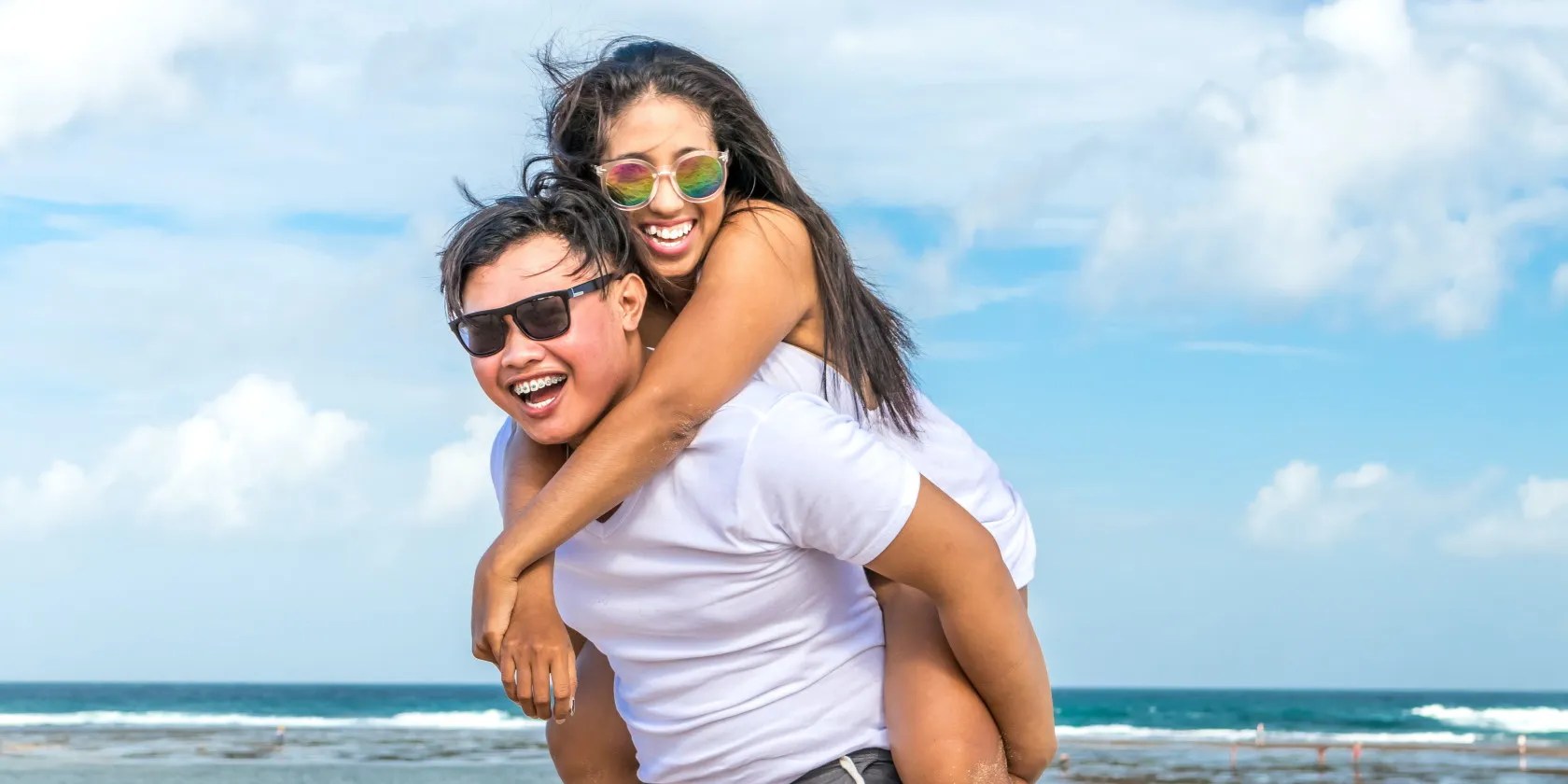 Happy man giving woman piggyback ride on the beach