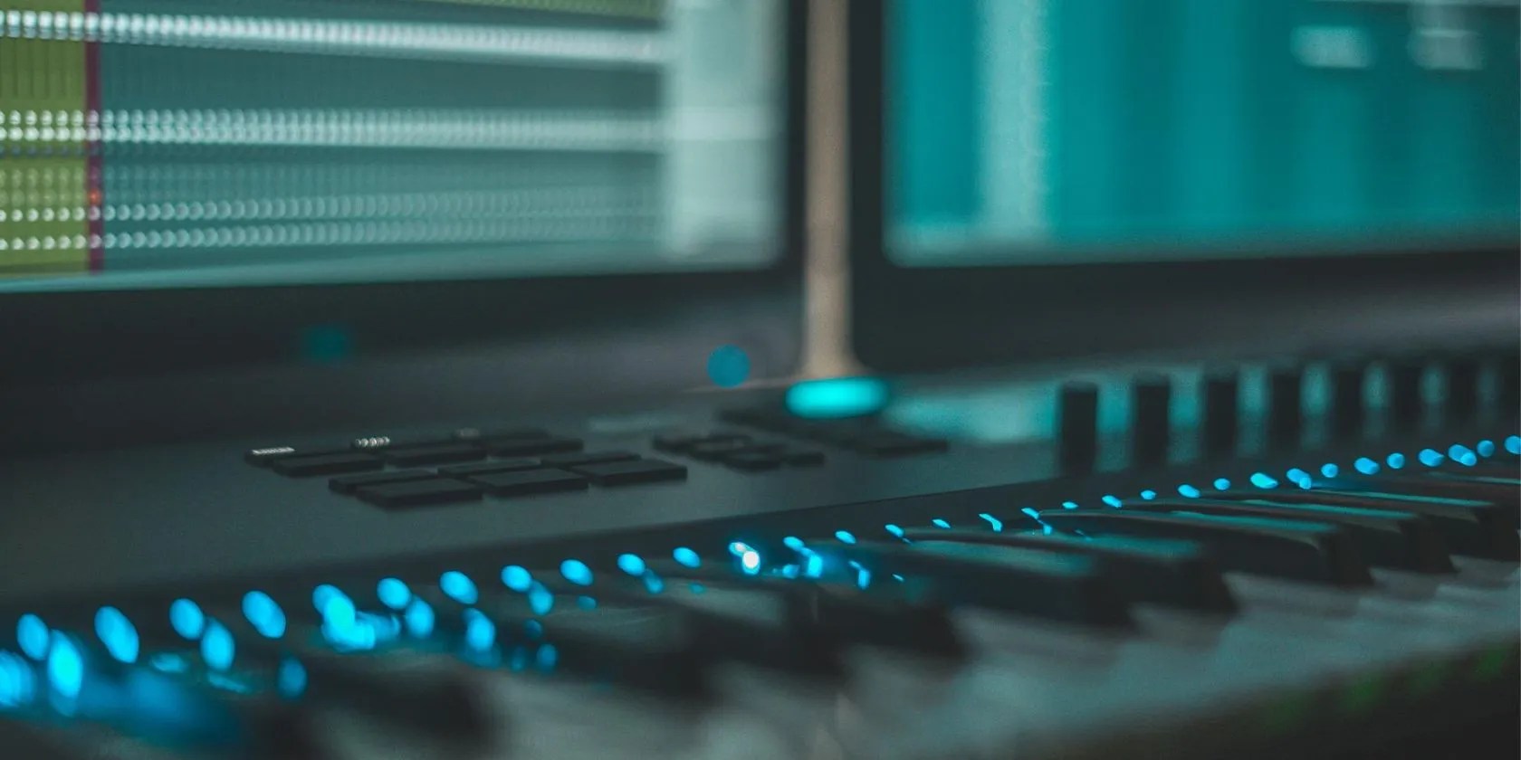 A MIDI keyboard on a desk with a Digital Audio Workstation open on a PC monitor