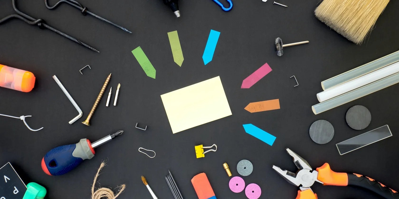 A top down photo of miscellaneous items like tools, paint brushes, sticky notes etc.