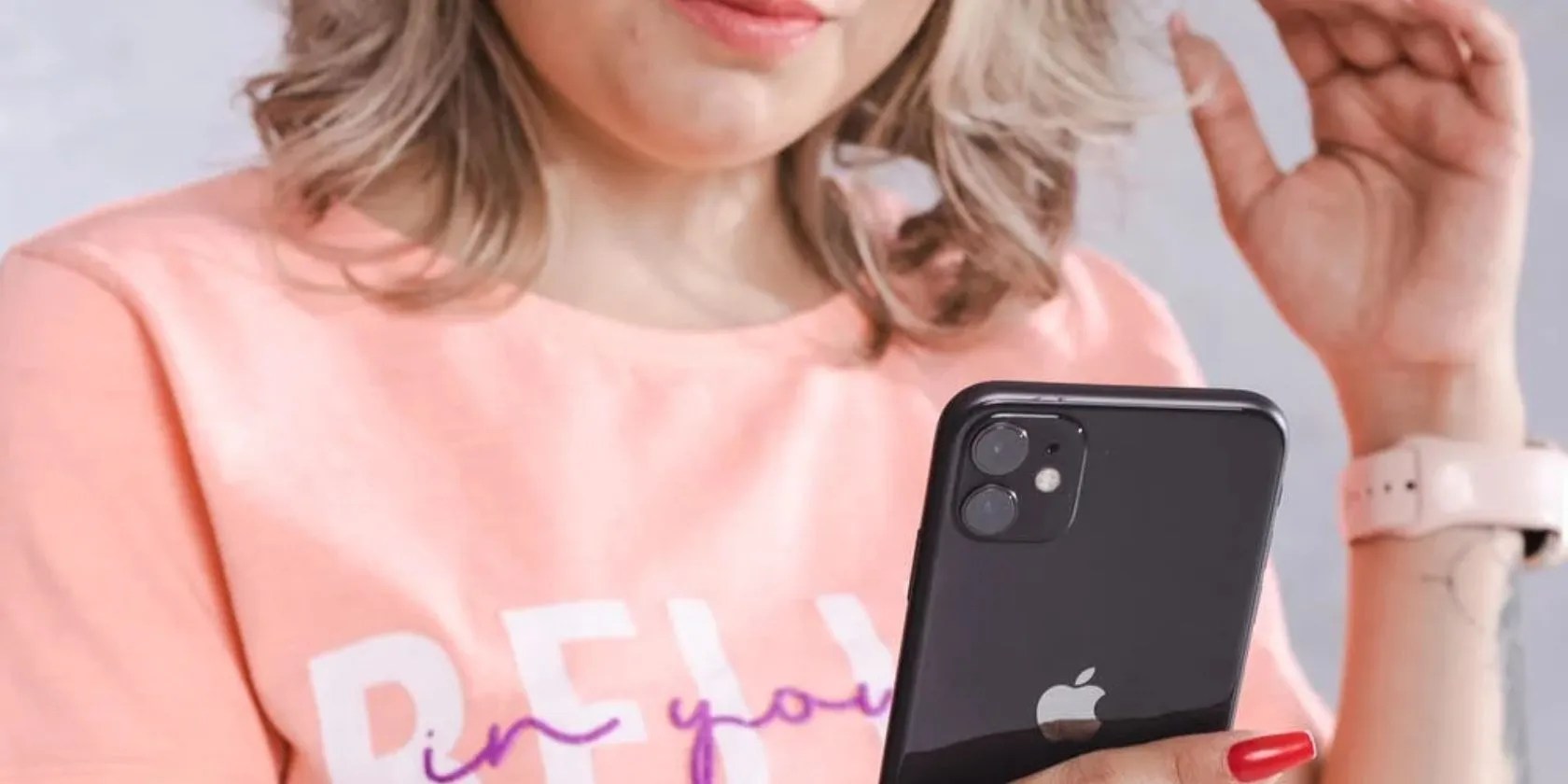 woman in peach top using black iphone