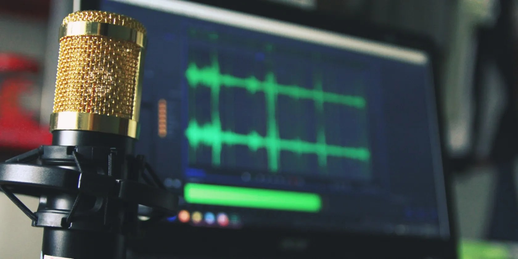 Gold microphone in front of laptop displaying music production software