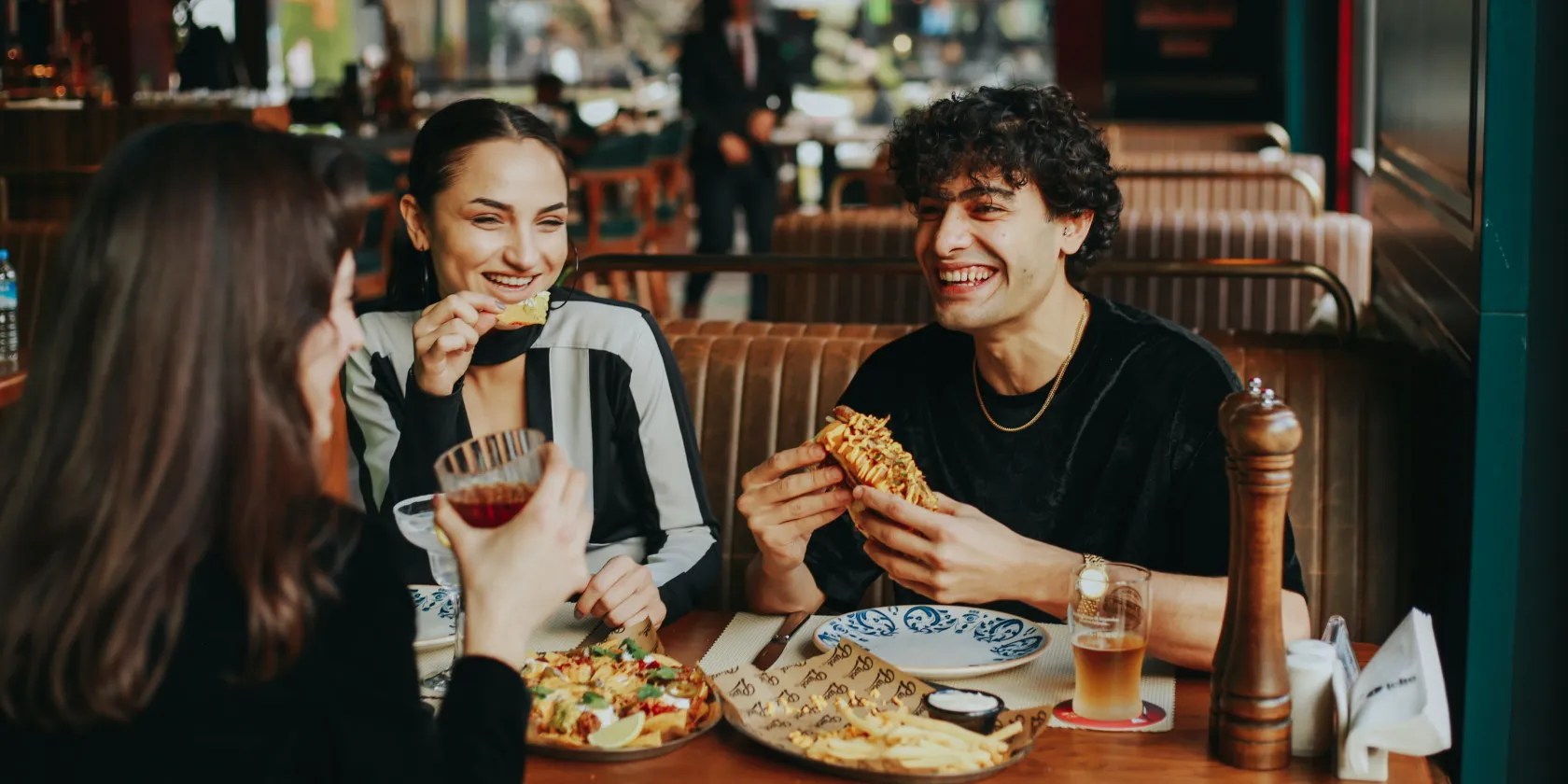 Happy group of friends eating and drinking in restaurant