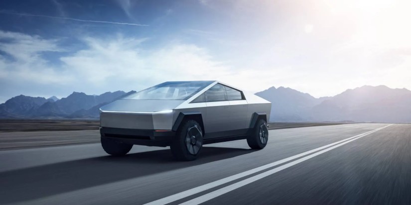 A Tesla Cybertruck on a highway with mountain in the background