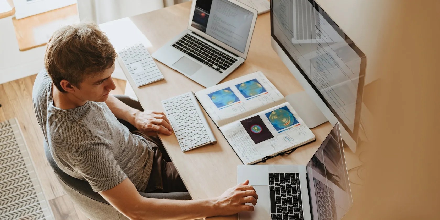 Man Using Two MacBooks and One iMac