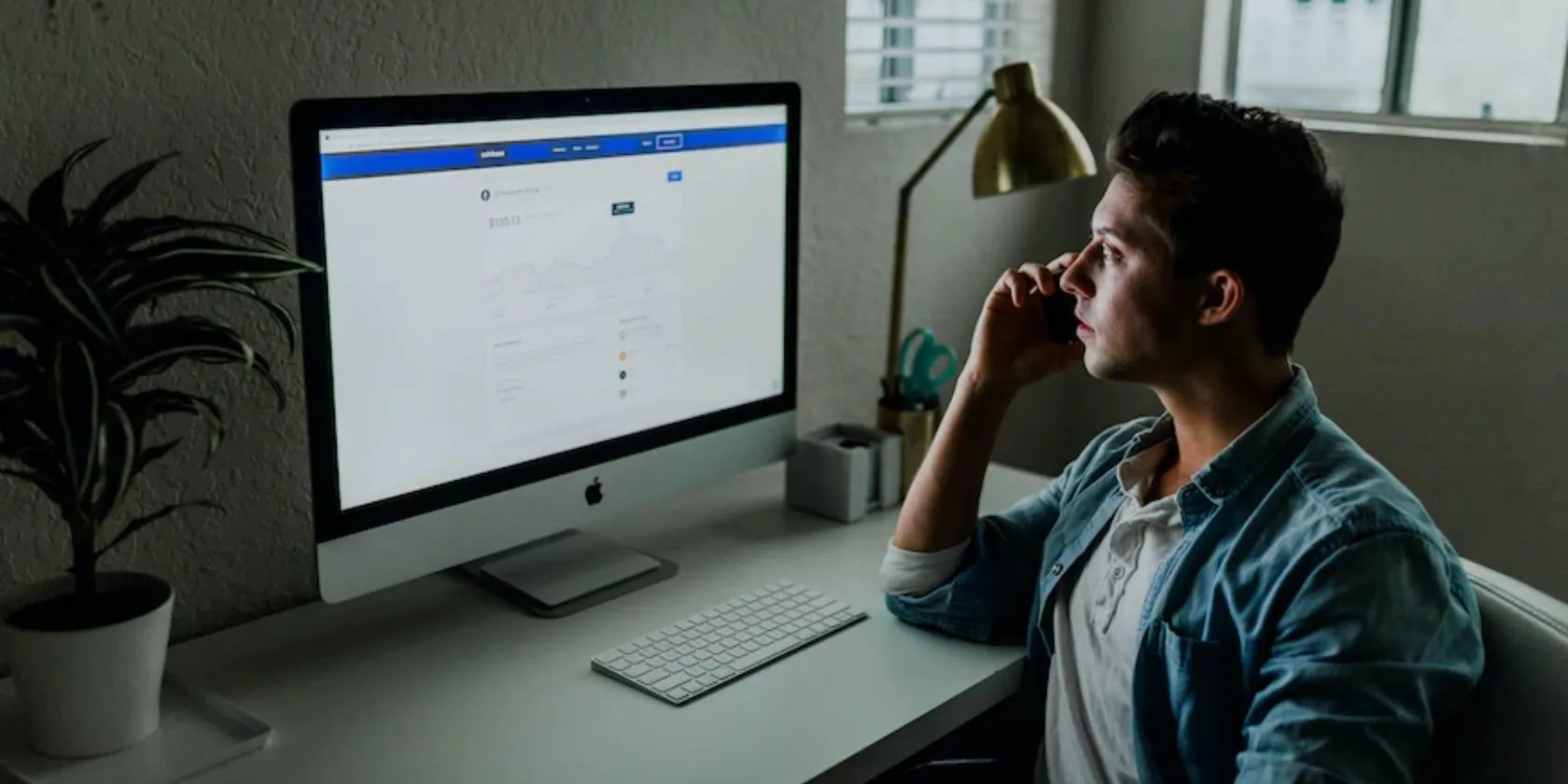 A man sitting on front of a large Apple Mac screen