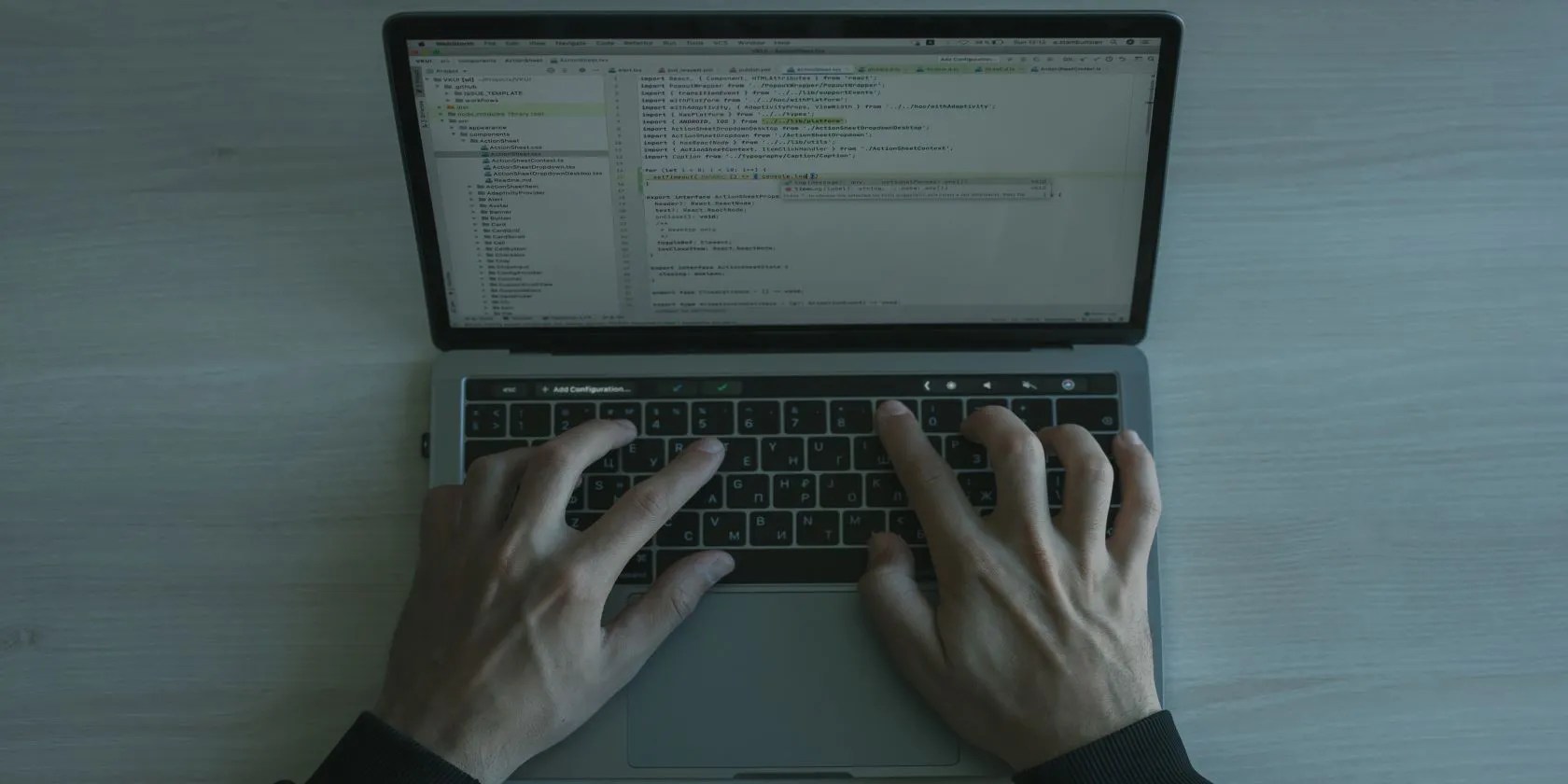 Laptop displaying code with two hands resting on the keyboard