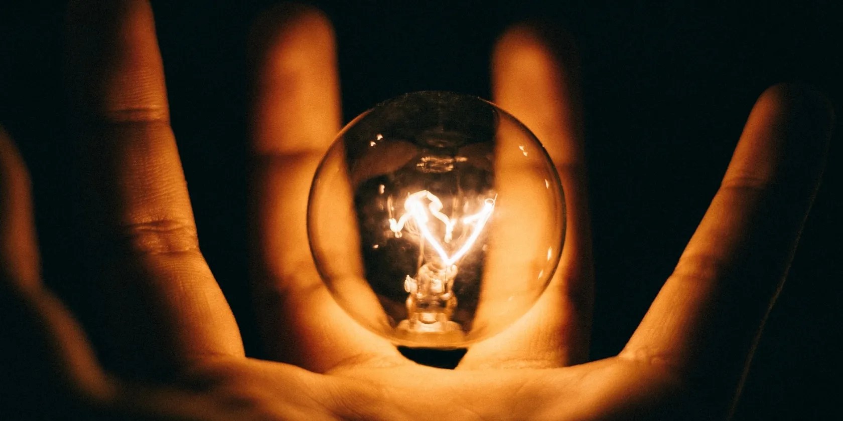 person holding lit lightbulb