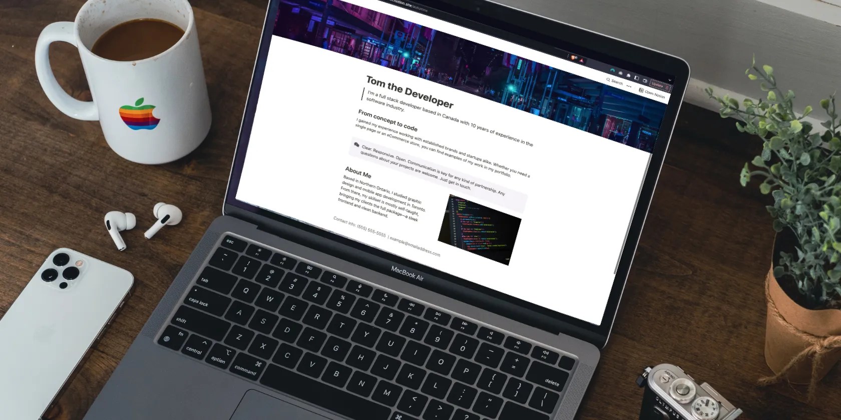 Laptop on a desk with a camera and phone