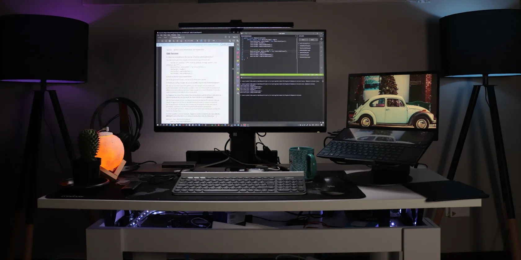 Code on computer on desk with car wallpaper on a second screen