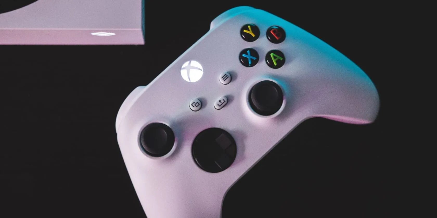 A photograph of a white Xbox Series S controller laying next to an Xbox Series S console