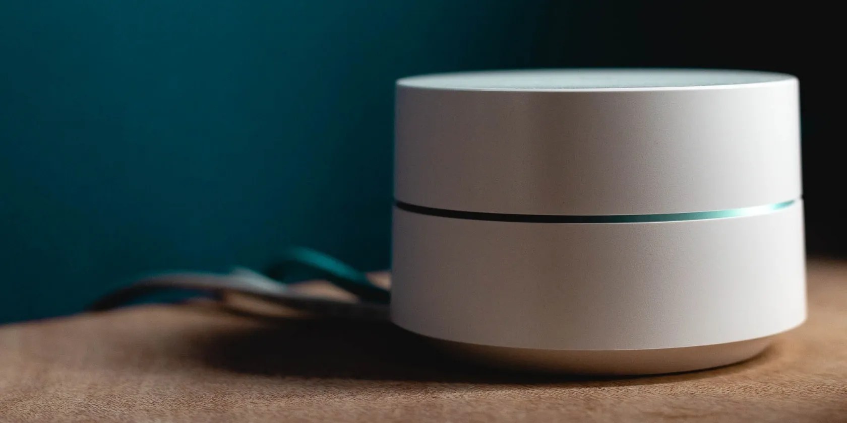 Google Wifi Mesh router over a table with cables on the background