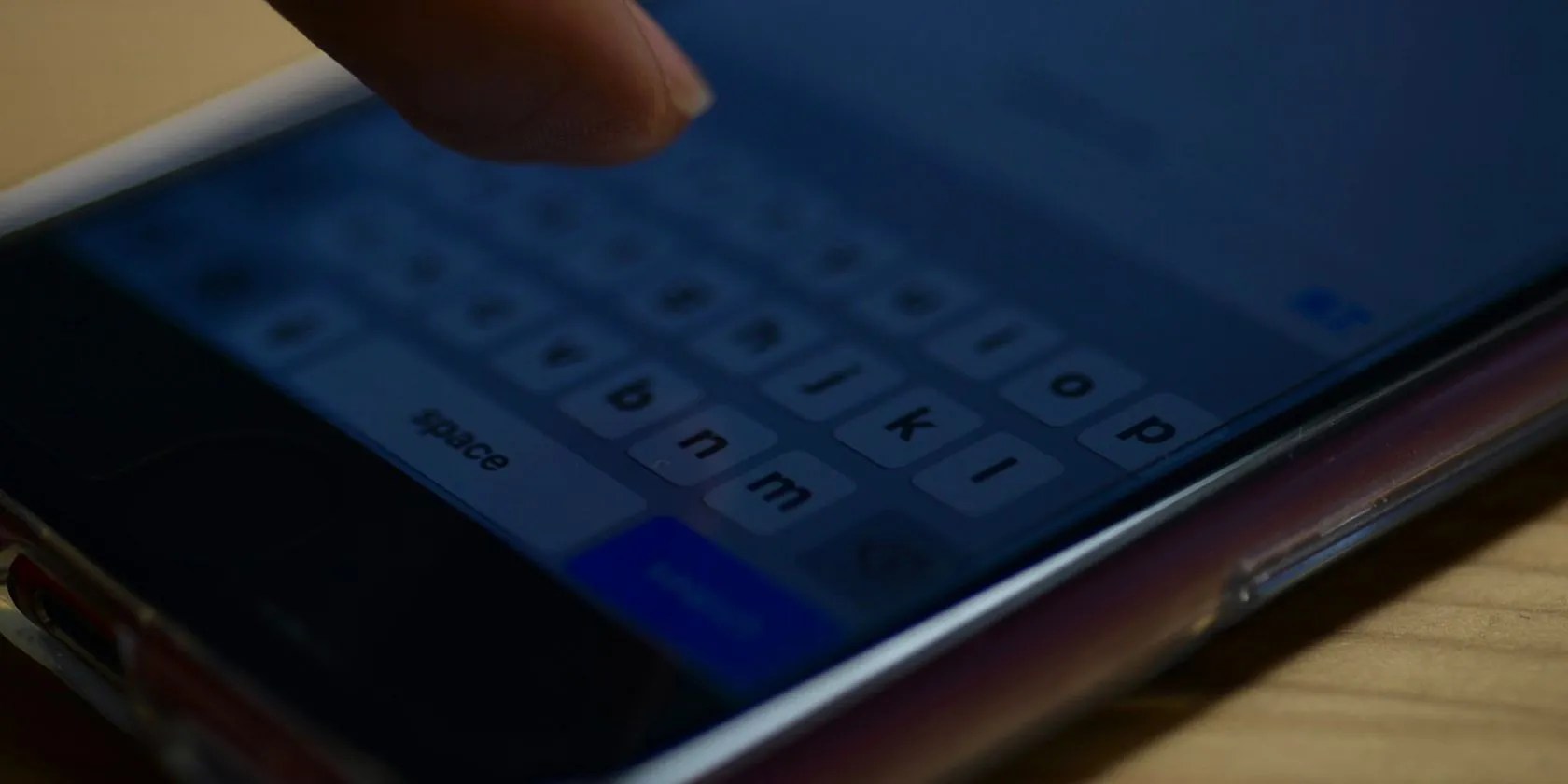 Finger seen above a smartphone keyboard