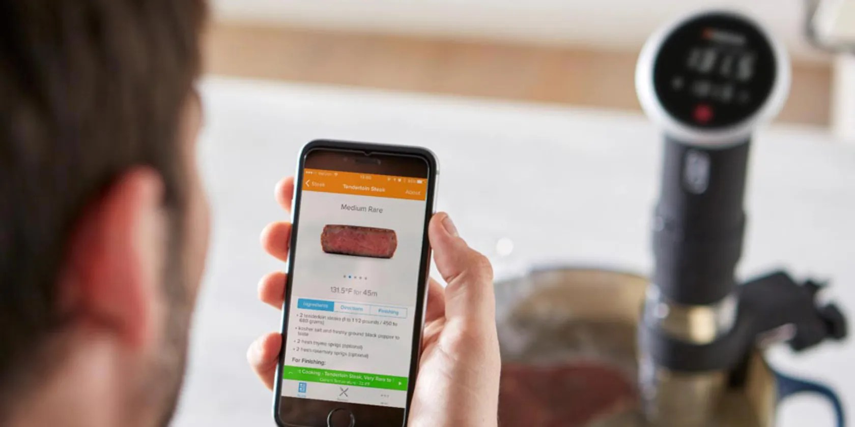Man holding smartphone in front of sous vide machine