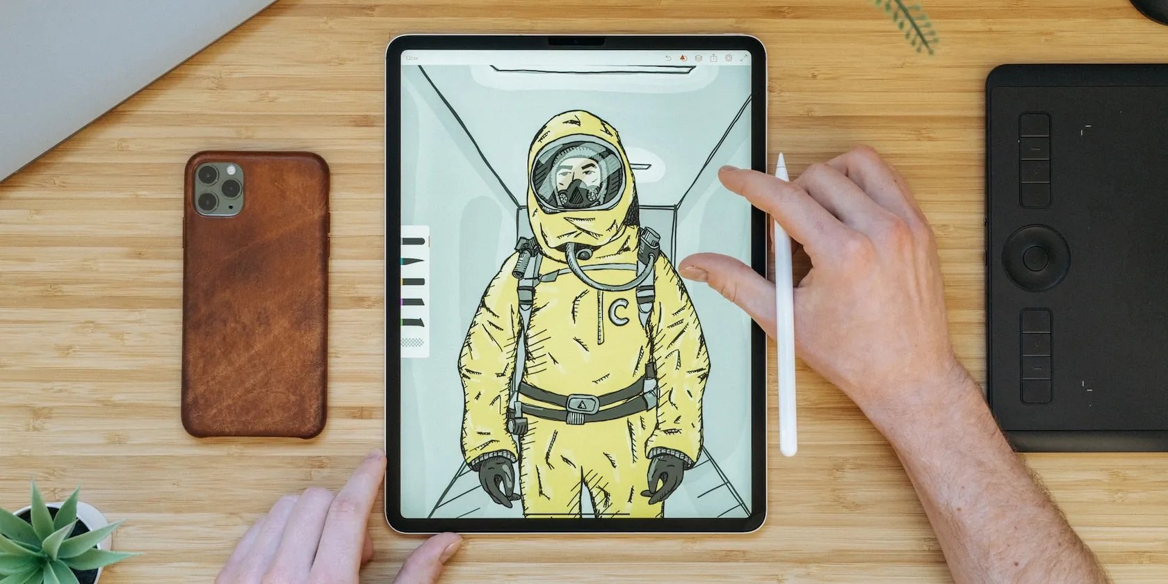 Top down photo of a desktop showing an iPad, iPhone and Apple Pencil.