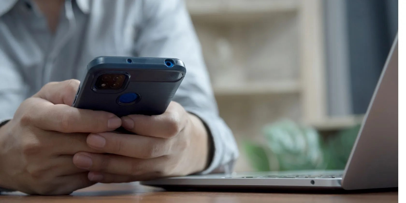 Man holds a smartphone next to a laptop