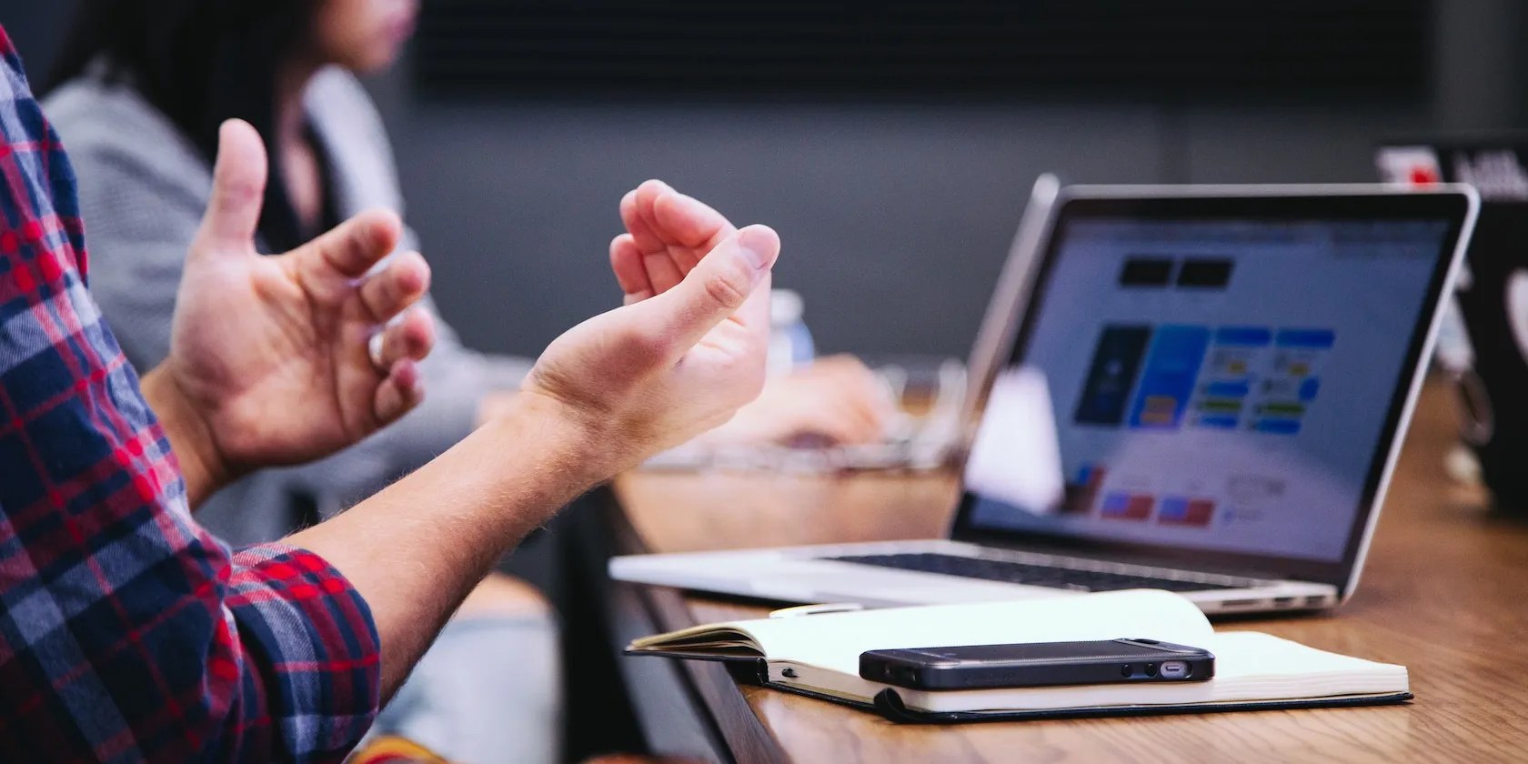 Man gesturing in frustration while using a laptop at a desk