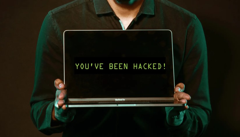 Man holding laptop that says you’ve been hacked