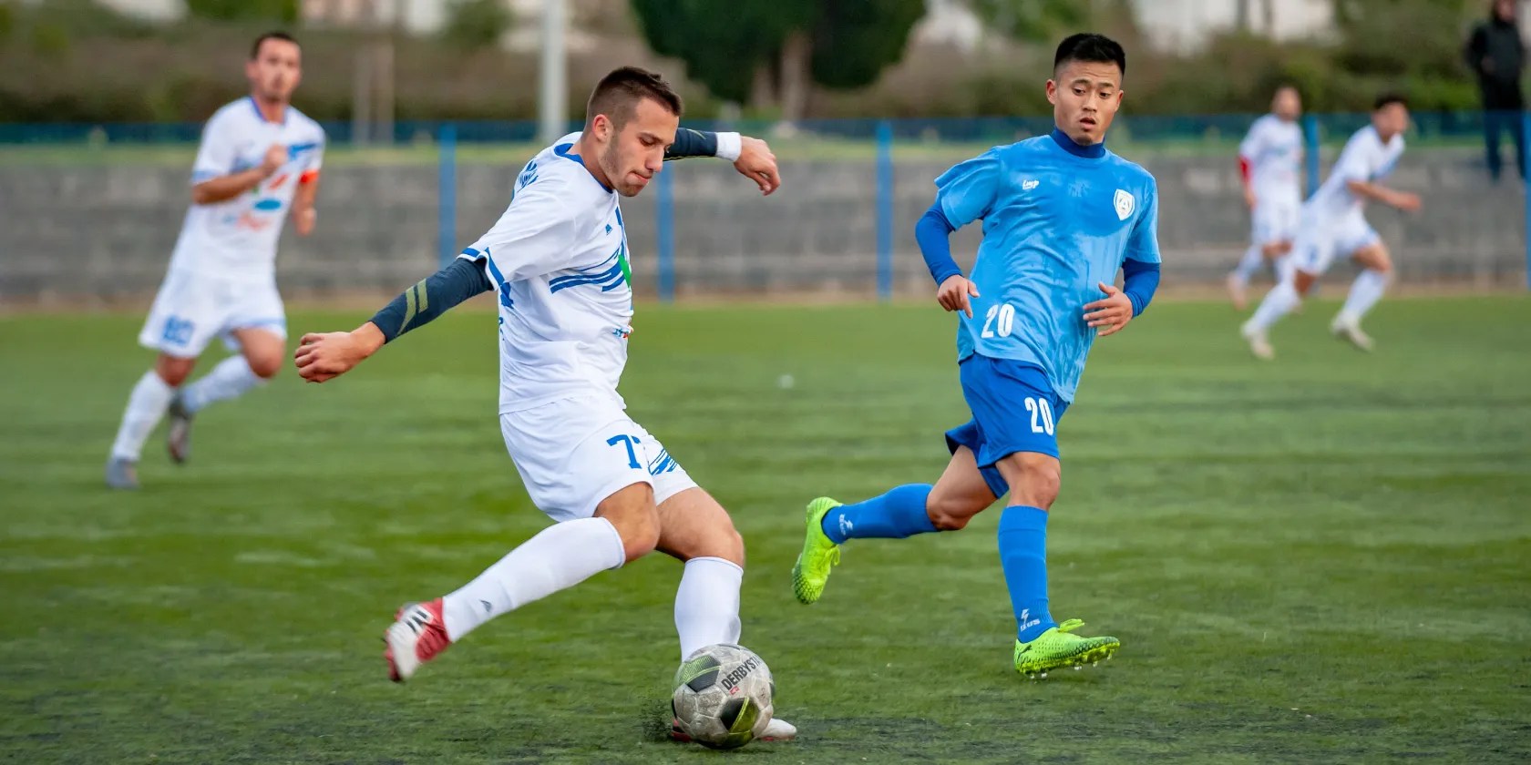 Person about to kick a soccer ball on the pitch