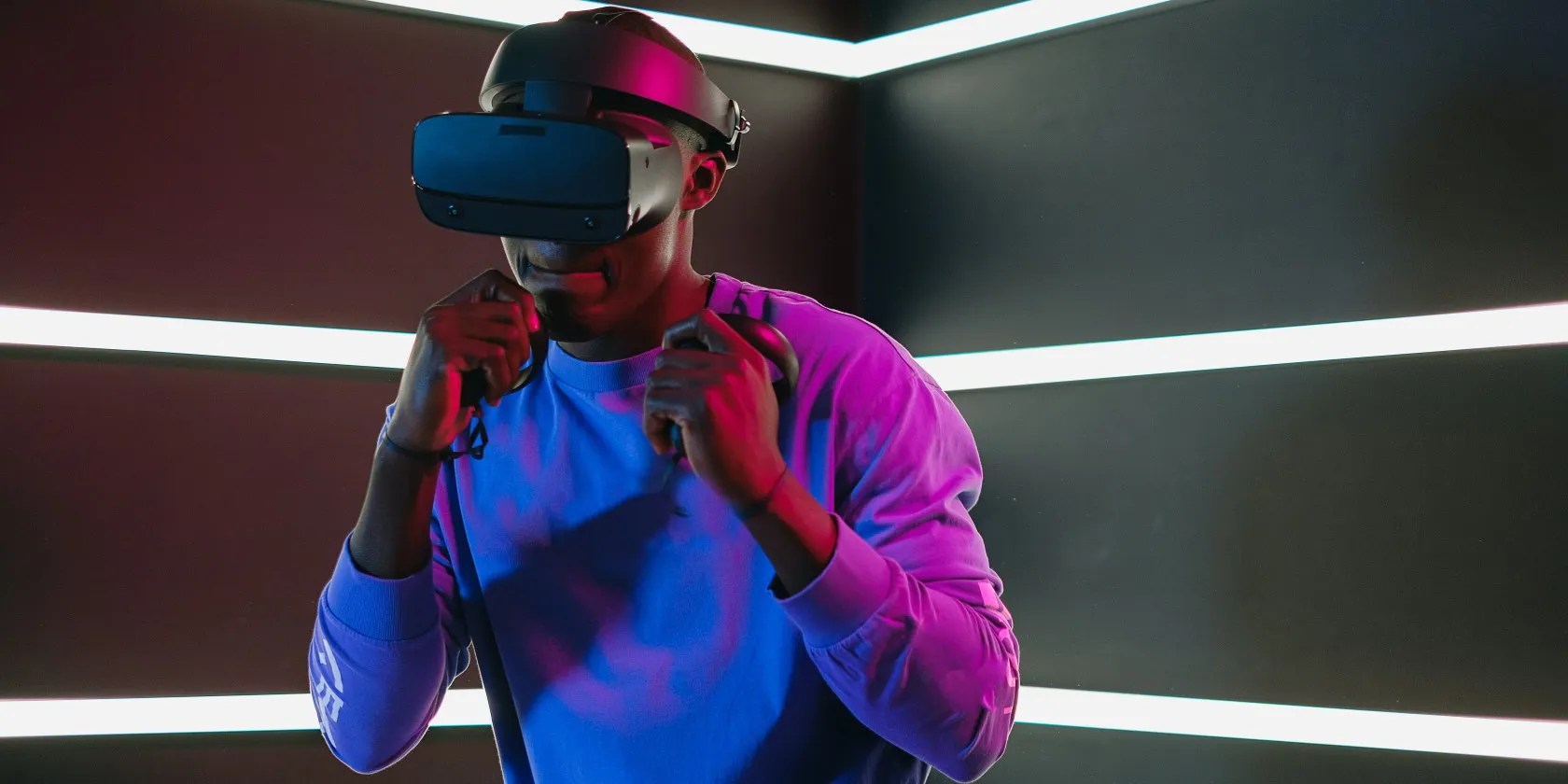 Man wearing VR headset and using VR controllers to play virtual reality VR game