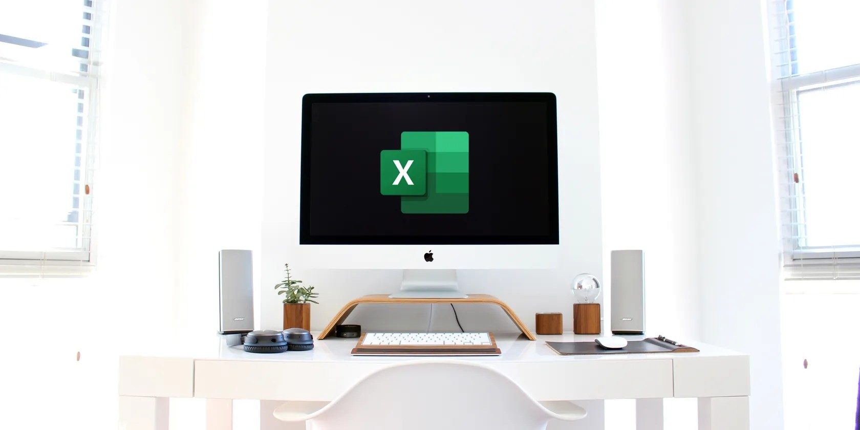 A computer monitor sitting on a desk with a blank screen with the Excel logo in the center.