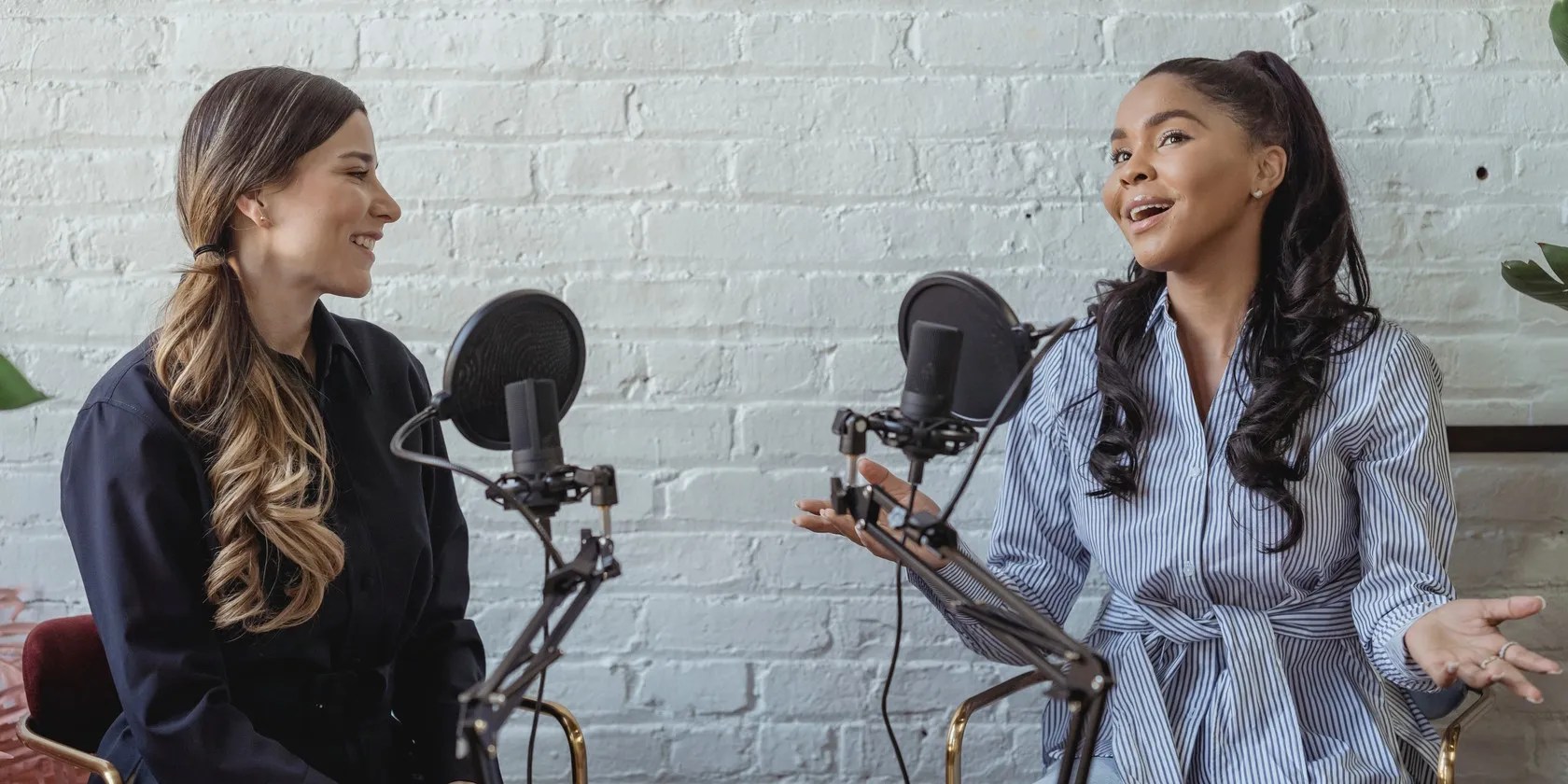 smiling women seated side by side speaking on podcast