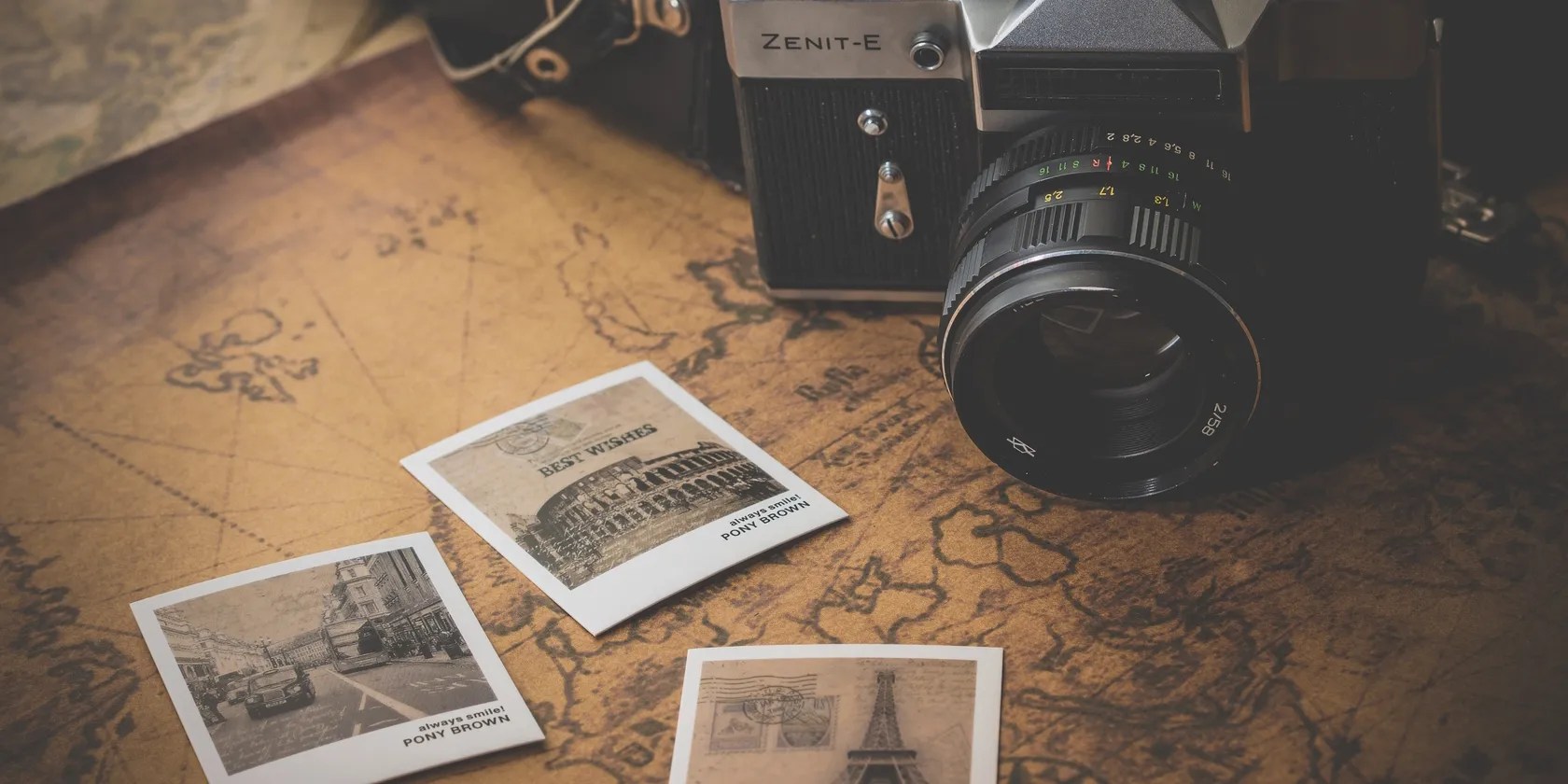 A vintage camera with a some old pictures sitting on top of a map.