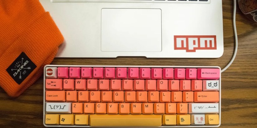 A developer setup with a keyboard and laptop sitting on a desk.
