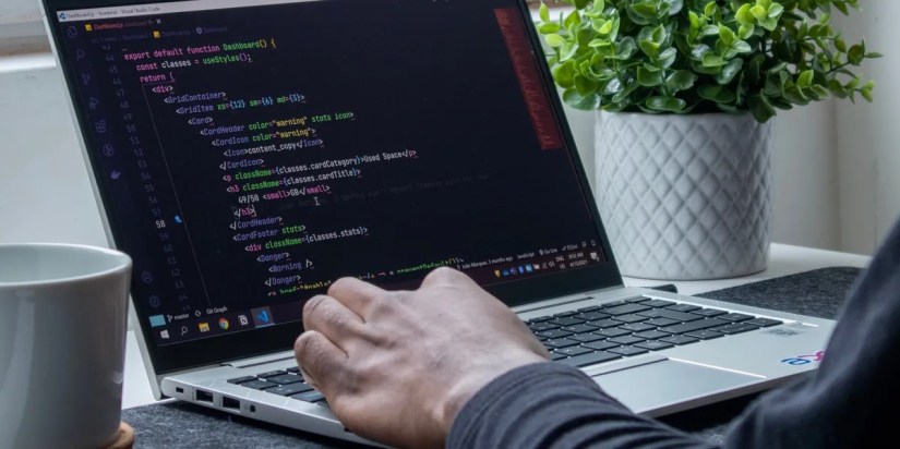 A developer writing React code on a laptop.