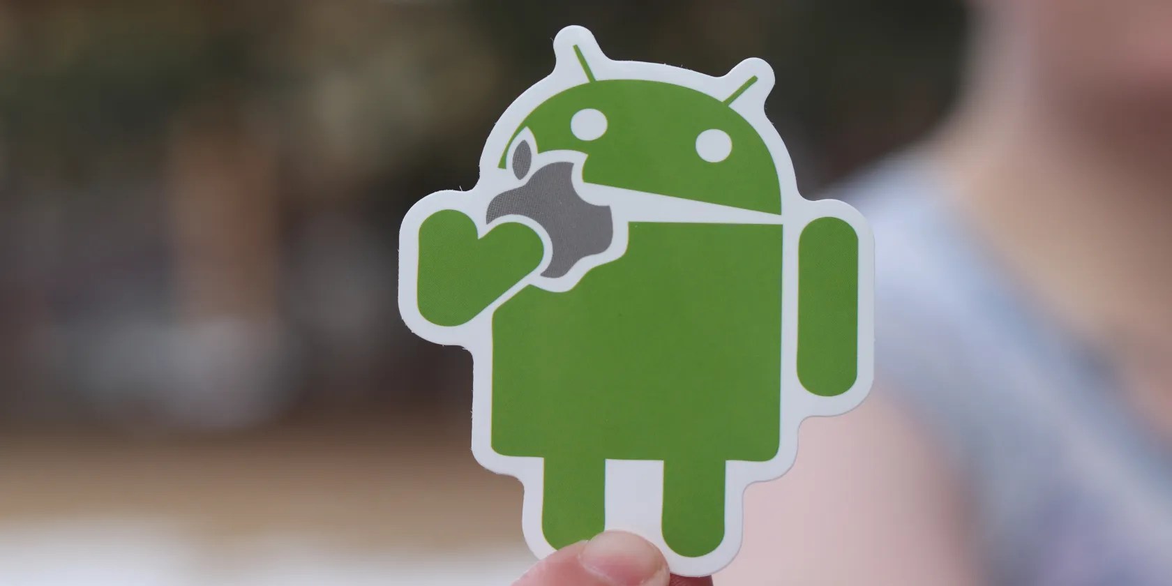 Android mascot eating Apple logo