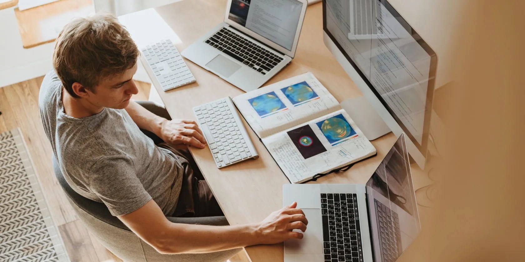 Man at multiple laptops with book on desk