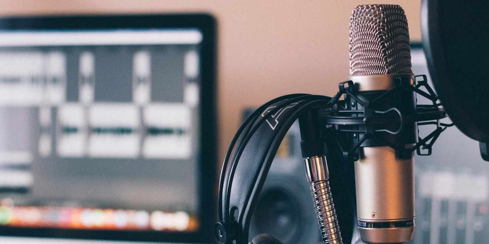 Silver microphone and black headphones with a PC monitor in the background