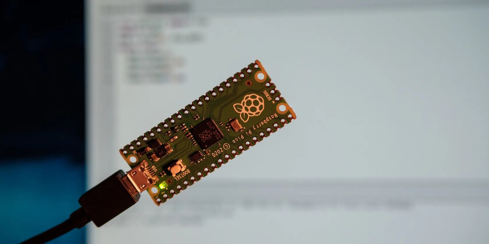 Raspberry Pi Zero board in front of a blurred computer screen